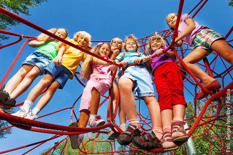 Klettergeräte benötigen eine Prüfpficht, das Bild zeigt Kinder die alle gemeinsam auf einem Klettergerät stehen.
