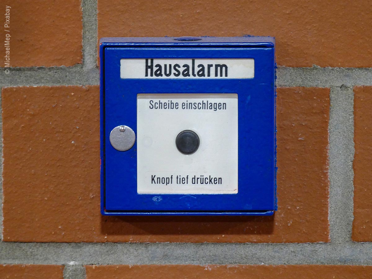 Hausalarm-Knopf in blau an einer Wand angebracht